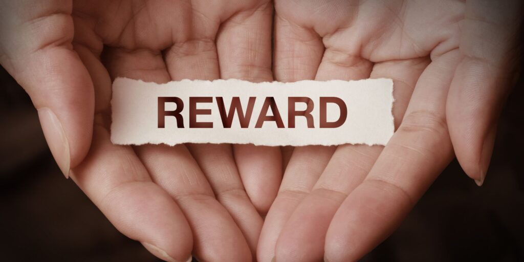 An image of two hands displaying a piece of ppaper that says "REWARD"